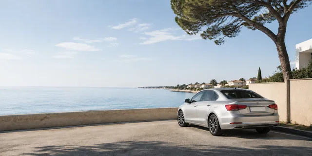 Silver car beside a sunlit Mediterranean coastal viewpoint